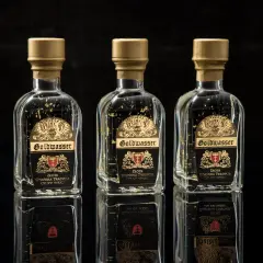 Trzy butelki Goldwasser z płatkami złota, symbolizujące gdańską tradycję. Sprawdź aktualną goldwasser cena.