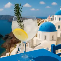 Orzeźwiający drink z cytryną i rozmarynem na tle greckiego akropolis. Idealny alkohol na wakacje.