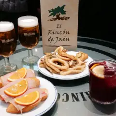 Dwa piwa Mahou, tapas z szynką i pomarańczą, smażone kalmary i sangria na stole w El Rincón de Jaén.