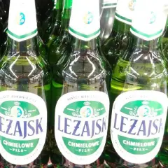 Rząd zielonych butelek piwa Leżajsk Chmielowe Pils. Idealne na letnie wieczory.