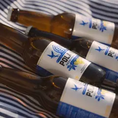 Kilka butelek piwa 0% na kocu w paski. Orzeźwiający napój na letni dzień.