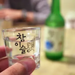 Szklaneczka z soju, na której widnieje napis "참이슬" i rysunek. Zastanawiasz się, soju ile procent?