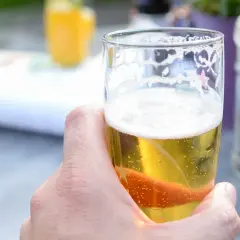 Chłodne piwo Miller w szklance, z bąbelkami i pianką, w letnim ogródku.