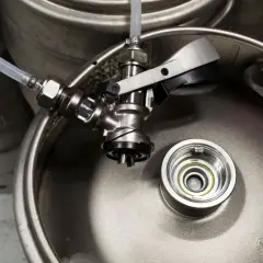 Metalowy keg piwa z podłączonym kranikiem i wężykiem. Gotowy do nalewania orzeźwiającego trunku.