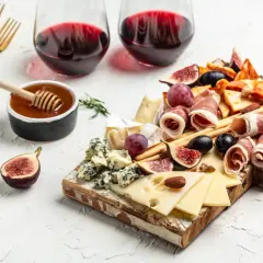 Deska serów i wędlin z winem wytrawnym, figami, winogronami i miodem. Idealna przekąska.