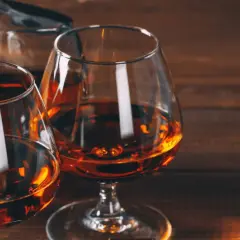 Dwa kieliszki z bursztynowym koniakiem i karafka na drewnianym stole. Idealny wieczór z brandy.