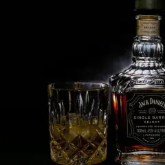 Butelka Jack Daniel's Single Barrel Select i szklanka z whisky na czarnym tle.