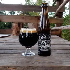 Piwo Imperator Bałtycki Sherry Oloroso BA w szkle i butelce na drewnianym stole.