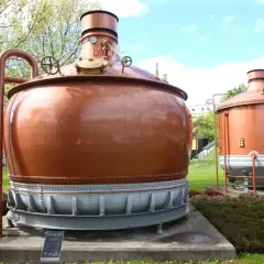 Dwa miedziane kadzie warzelnicze, świadkowie historii piwa specjal, stoją dumnie na trawniku.