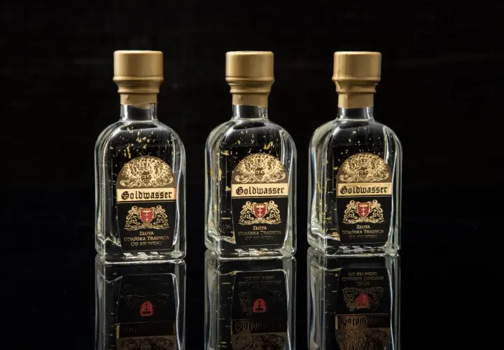 Trzy butelki Goldwasser z płatkami złota, symbolizujące gdańską tradycję. Sprawdź aktualną goldwasser cena.