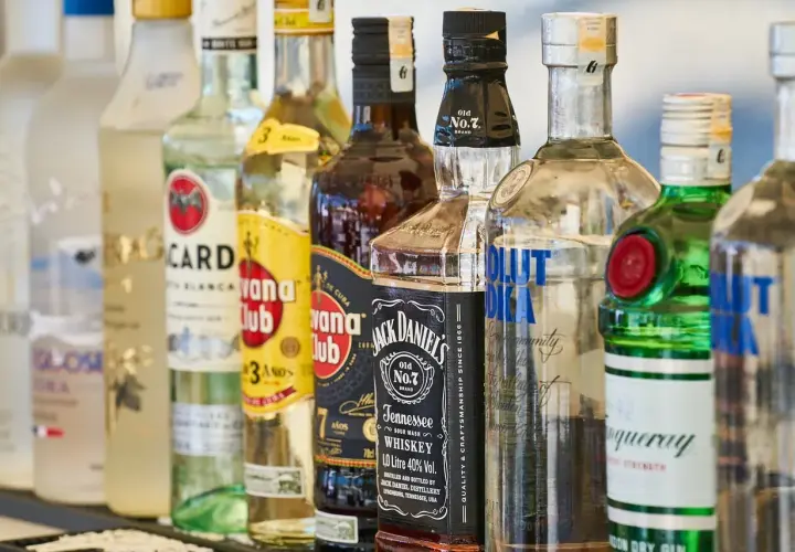 Rząd butelek alkoholi: Bacardi, Havana Club, Jack Daniel's, Absolut Vodka, Tanqueray. Idealne na mocne piwo i drinki.