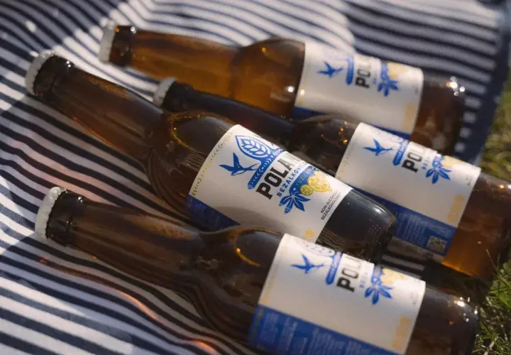 Kilka butelek piwa 0% na kocu w paski. Orzeźwiający napój na letni dzień.