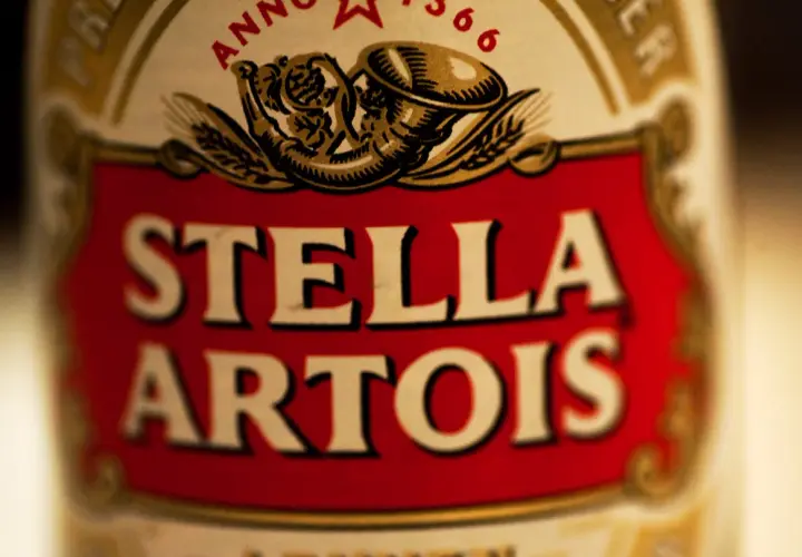 Zbliżenie na etykietę piwa Stella Artois. Czerwone tło z białym napisem.