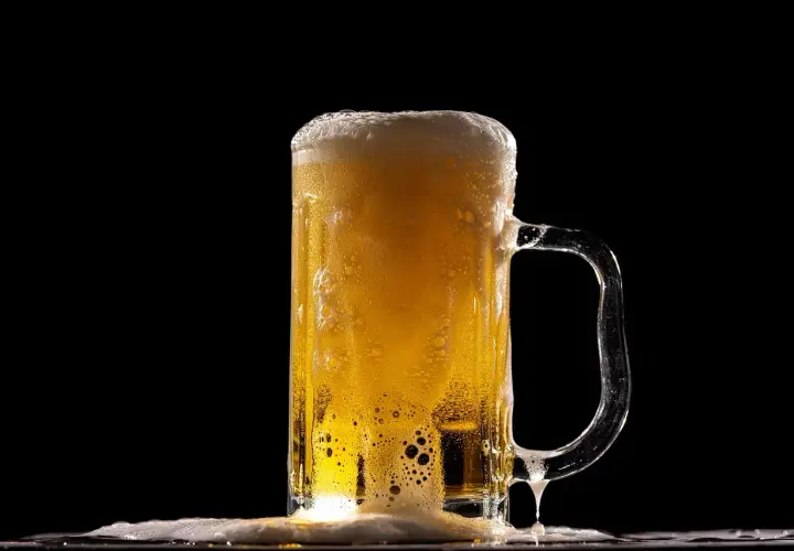 Piana z piwa Lech Pils spływa po szklance, tworząc orzeźwiający widok.