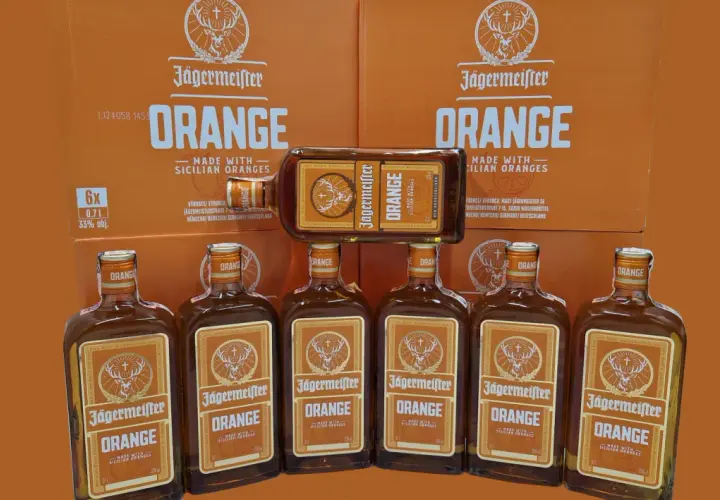 Jägermeister Orange, jeden z rodzajów Jägermeister, w butelkach i kartonach, z pomarańczowym motywem.