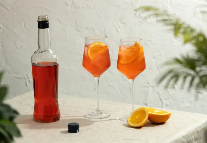 Butelka Aperolu i dwa drinki z pomarańczą. Aperol co to? To idealny aperitif na letnie popołudnie.