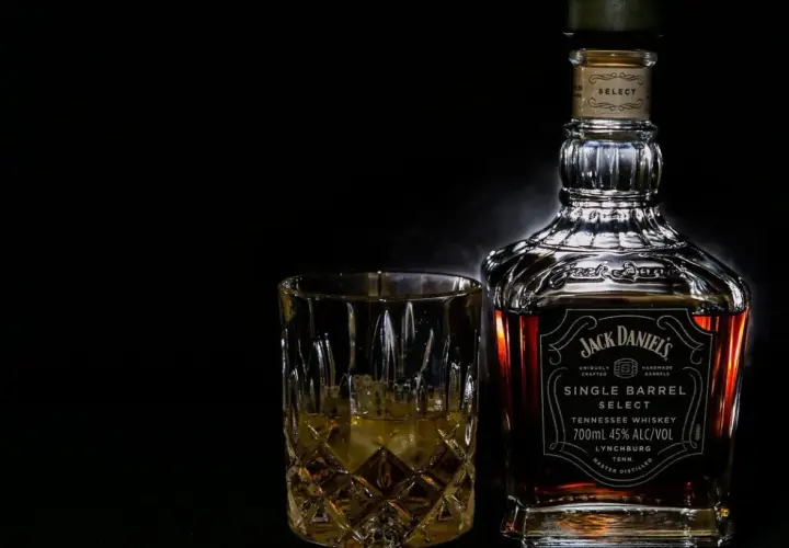 Butelka Jack Daniel's Single Barrel Select i szklanka z whisky na czarnym tle.