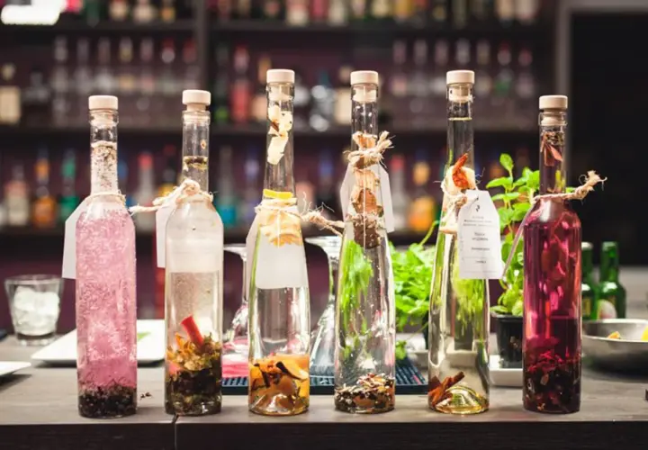 Sześć butelek z nalewkami, jedna z różową zawartością, druga z przyprawami. Zastanawiasz się, ile procent ma tequila?