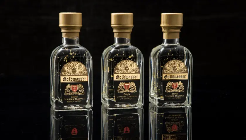 Trzy butelki Goldwasser z płatkami złota, symbolizujące gdańską tradycję. Sprawdź aktualną goldwasser cena.