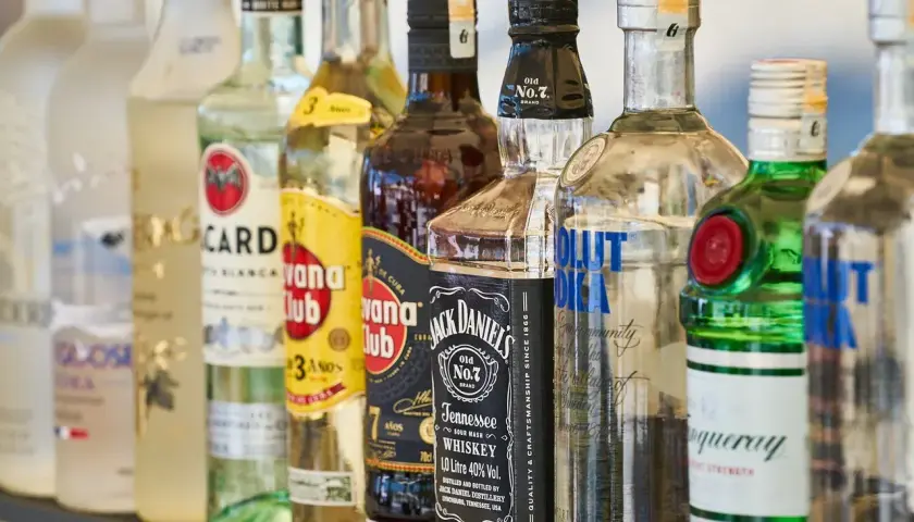 Rząd butelek alkoholi: Bacardi, Havana Club, Jack Daniel's, Absolut Vodka, Tanqueray. Idealne na mocne piwo i drinki.