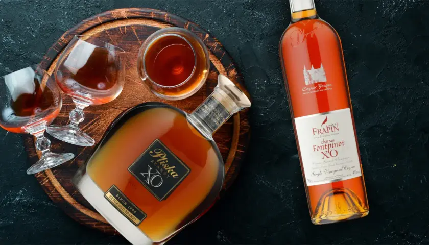 Butelka i kieliszki z bursztynowym brandy. To jest co to jest brandy - szlachetny trunek.