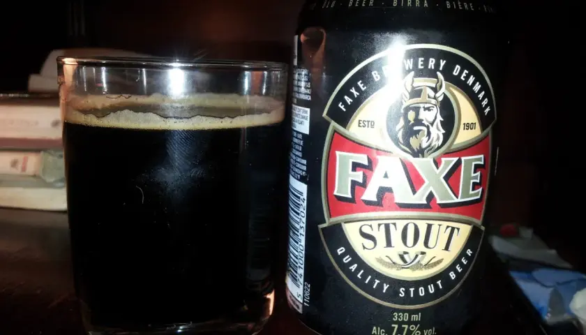 Szklanka ciemnego piwa obok puszki piwa Faxe Stout. Idealne na wieczór z dobrą książką.