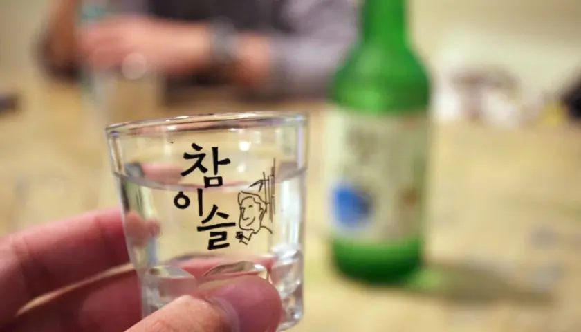 Szklaneczka z soju, na której widnieje napis "참이슬" i rysunek. Zastanawiasz się, soju ile procent?