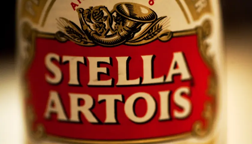 Zbliżenie na etykietę piwa Stella Artois. Czerwone tło z białym napisem.