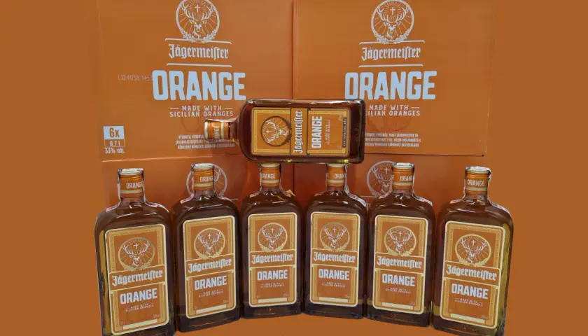 Jägermeister Orange, jeden z rodzajów Jägermeister, w butelkach i kartonach, z pomarańczowym motywem.