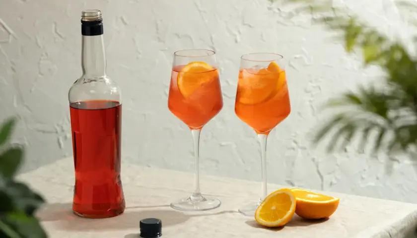 Butelka Aperolu i dwa drinki z pomarańczą. Aperol co to? To idealny aperitif na letnie popołudnie.