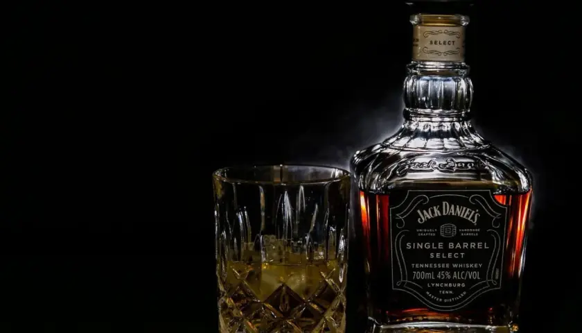 Butelka Jack Daniel's Single Barrel Select i szklanka z whisky na czarnym tle.