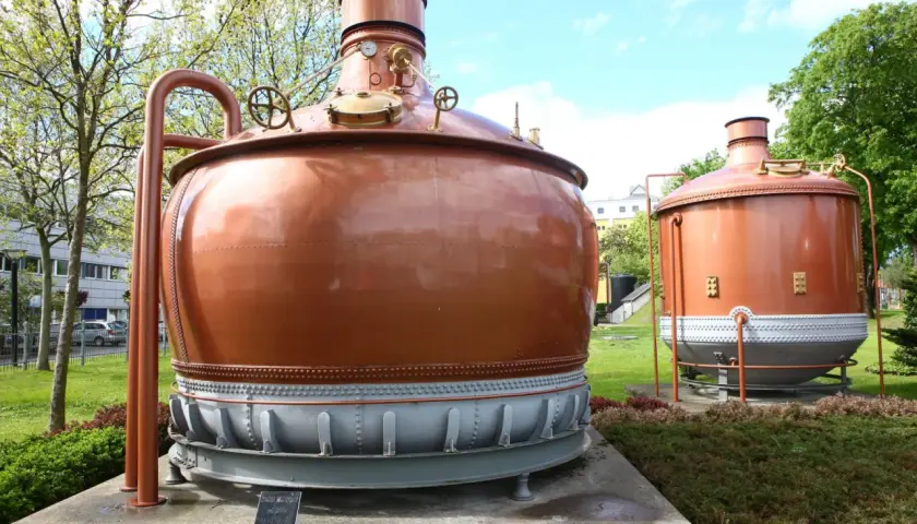 Dwa miedziane kadzie warzelnicze, świadkowie historii piwa specjal, stoją dumnie na trawniku.