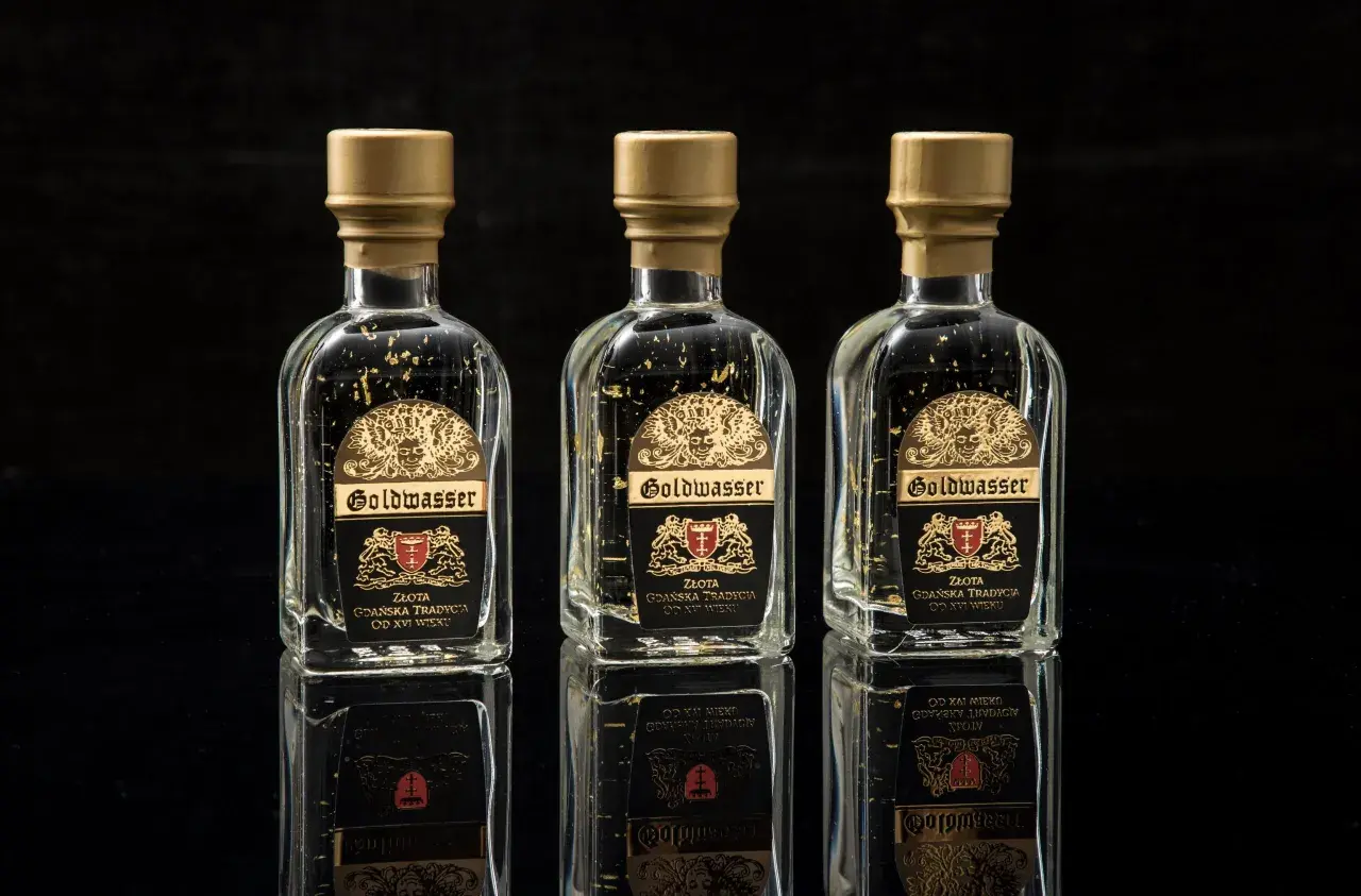 Trzy butelki Goldwasser z płatkami złota, symbolizujące gdańską tradycję. Sprawdź aktualną goldwasser cena.
