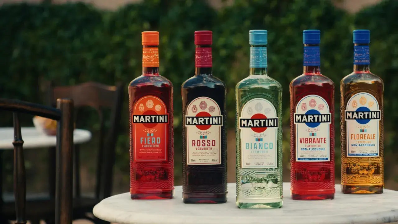 Pięć butelek Martini o różnych kolorach i smakach, stojących na stole na zewnątrz.
