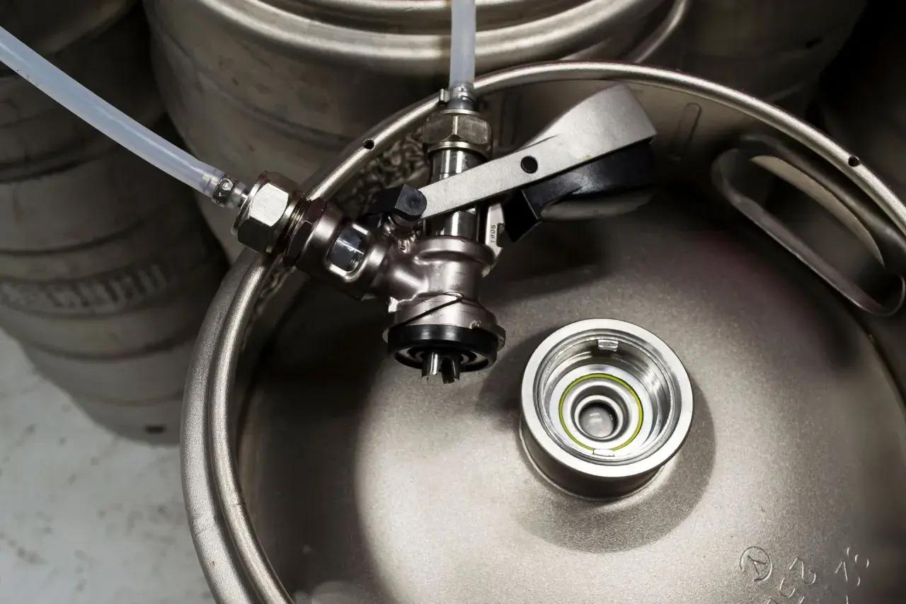 Metalowy keg piwa z podłączonym kranikiem i wężykiem. Gotowy do nalewania orzeźwiającego trunku.