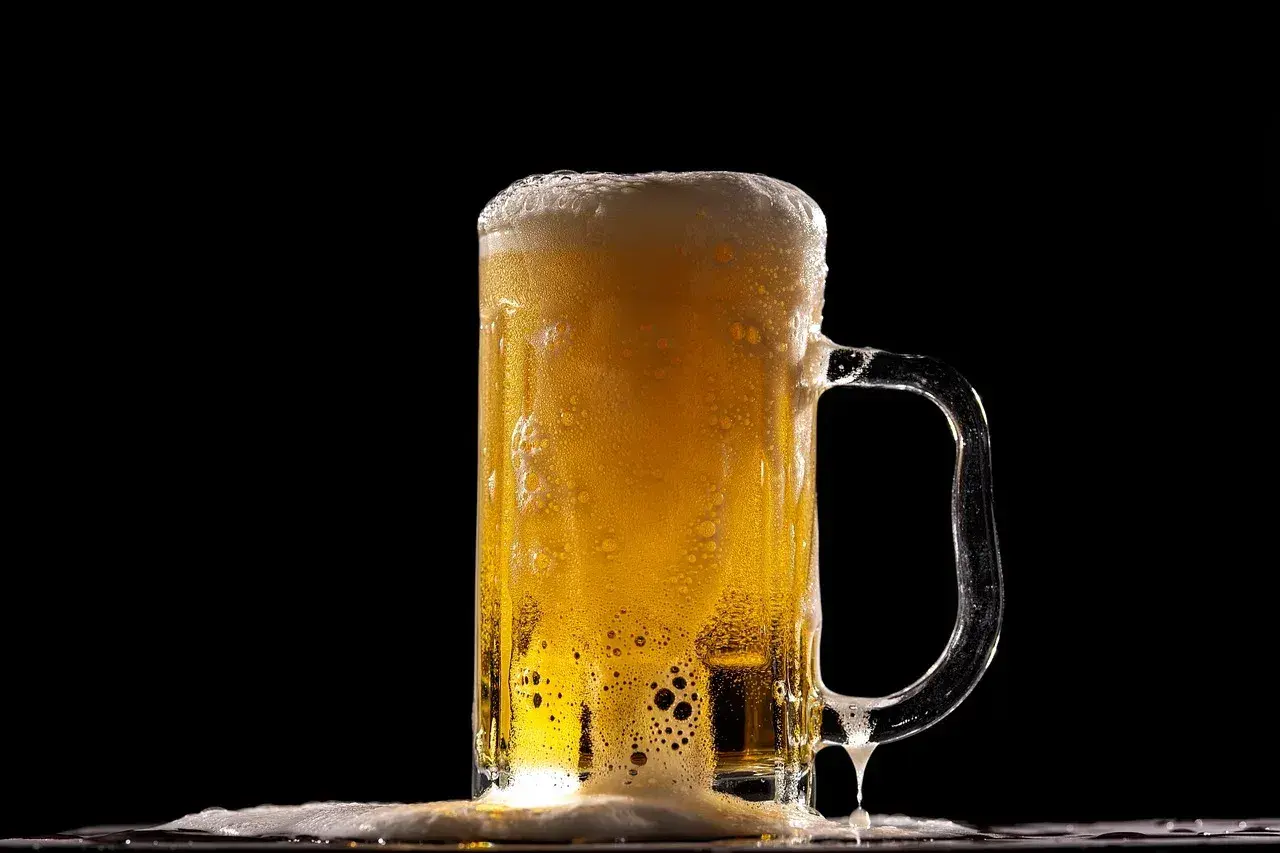 Piana z piwa Lech Pils spływa po szklance, tworząc orzeźwiający widok.