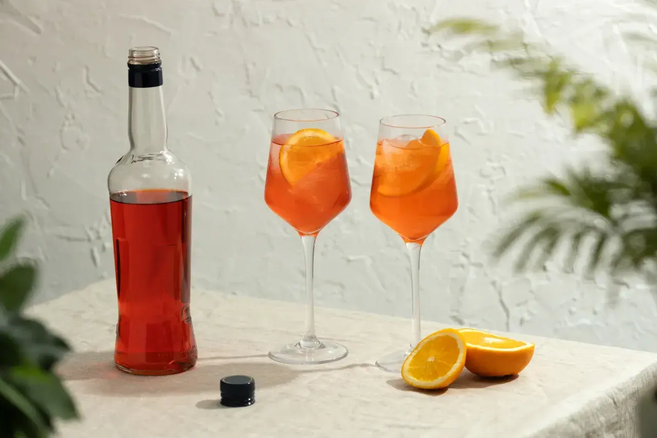 Butelka Aperolu i dwa drinki z pomarańczą. Aperol co to? To idealny aperitif na letnie popołudnie.