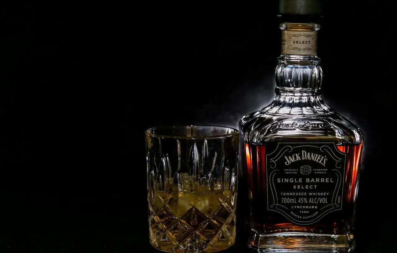 Butelka Jack Daniel's Single Barrel Select i szklanka z whisky na czarnym tle.