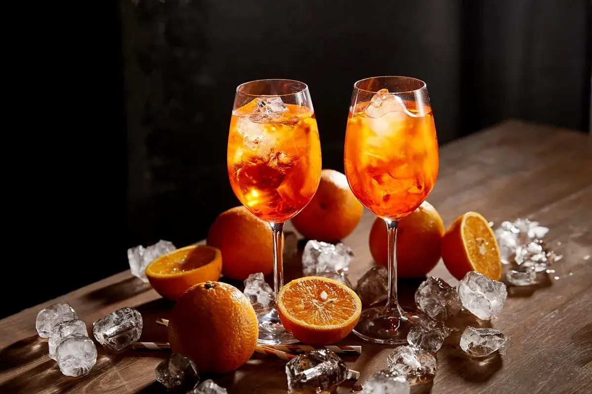 Dwa drinki Aperol Spritz z lodem i pomarańczą. Sprawdź atrakcyjną aperol cena!