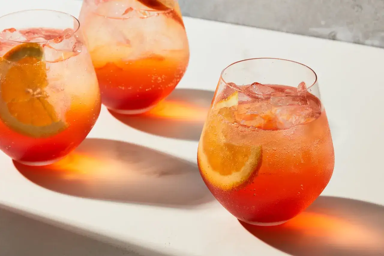 Trzy orzeźwiające drinki z pomarańczą i lodem, idealne na cin cin aperitivo.