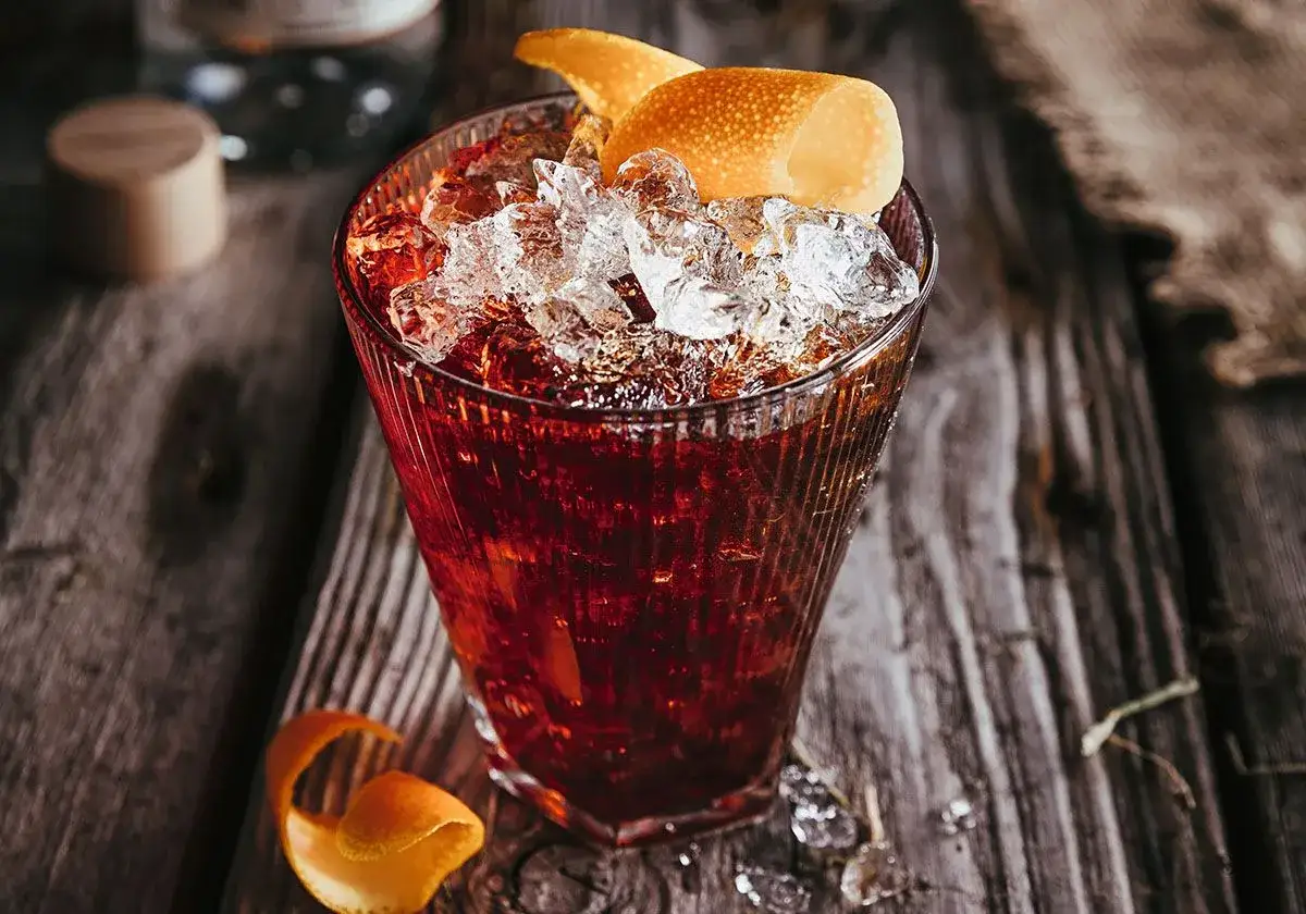 Ciemny, orzeźwiający drink z lodem i skórką pomarańczy, idealny na wieczór z Koskenkorva.