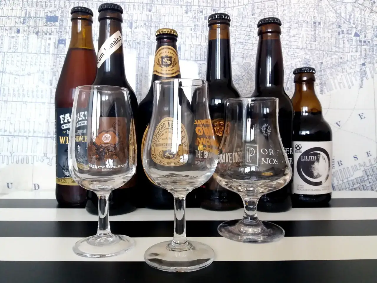 Butelki z piwem i kieliszki do degustacji. W tle mapa, na stole pasy. Idealne do degustacji piwa typu ipa piwo.