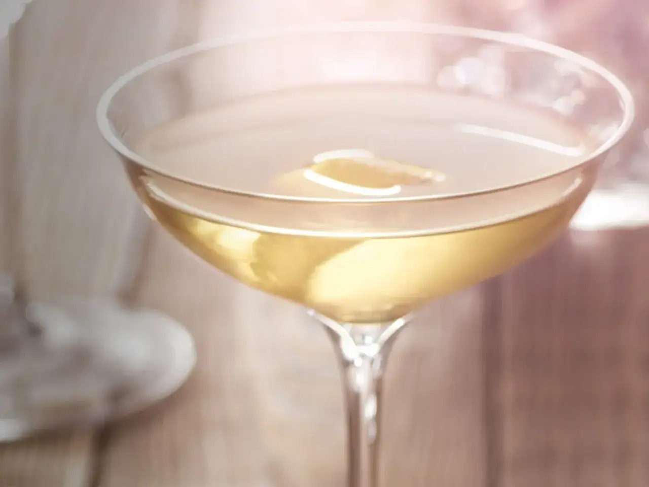 Elegancki kieliszek z drinkiem martini extra dry, ozdobiony plasterkiem cytryny, na drewnianym tle.