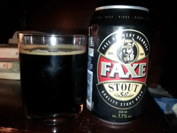 Szklanka ciemnego piwa obok puszki piwa Faxe Stout. Idealne na wieczór z dobrą książką.